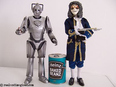 Toy cyberman and a toy clockwork droid next to a tin of baked beans