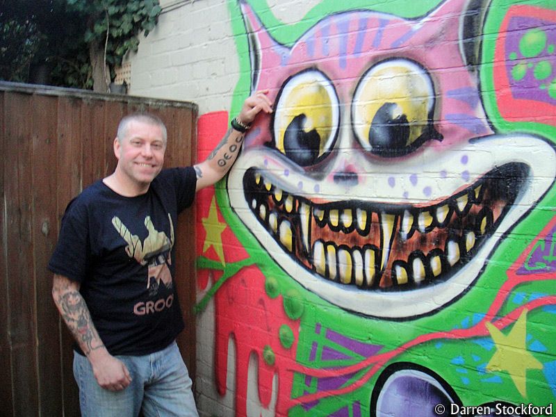 Gary Davidson, author of Zealot In Wonderland, next to a Cheshire Cat mural at The Gardener's Arms, Oxford